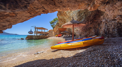Kayaks resting beside a natural cave opening on a hidden Mediterranean inlet