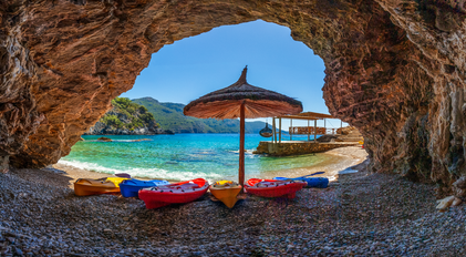 Panoramic cavefront view with kayaks overlooking a turquoise Mediterranean inlet