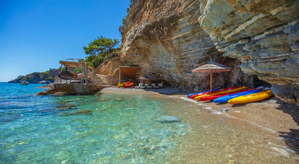 Colorful kayaks lined along a quiet shoreline in a hidden Mediterranean cove