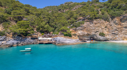 Aerial view of layered waterfront decks beside caves on a turquoise bay