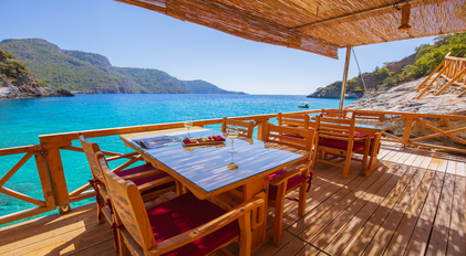 Sea-view dining deck overlooking a calm turquoise Mediterranean bay