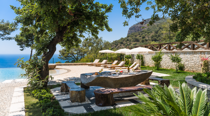 Outdoor stone-table lunch prepared by a private chef overlooking an infinity pool and the sea