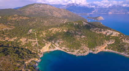 Aerial view of forested Mediterranean peninsula with secluded coves and clear blue waters