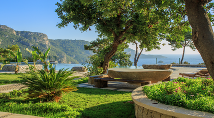 Secluded garden terrace framed by stone landscaping and Mediterranean views