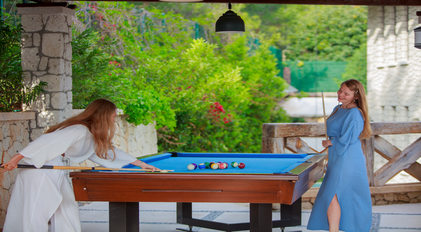 Guests enjoying a quiet pool table game on a shaded Mediterranean terrace