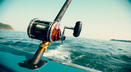 Deep-sea fishing reel mounted on boat cruising over blue Mediterranean waters