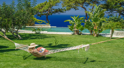 Garden hammock facing an infinity pool and deep-blue Mediterranean sea