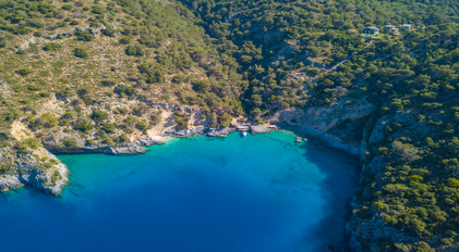 Aerial panorama of turquoise Mediterranean bay embraced by lush green cliffs