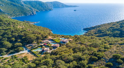 Aerial view of forest-surrounded villas overlooking the dramatic Mediterranean coastline
