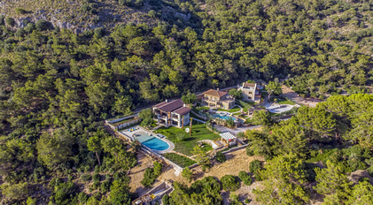 Aerial view of private hillside estate surrounded by lush Mediterranean forest