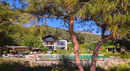 Lagoon-style pool villa framed by lush forest and Mediterranean scenery