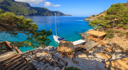 Coastal deck overlooking turquoise waters and forested cliffs on a secluded Mediterranean peninsula