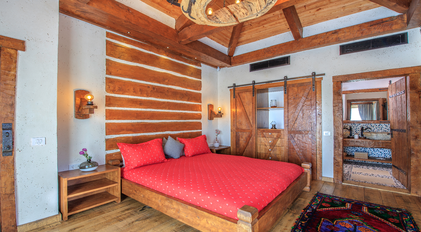 Bedroom with rustic wood paneling and handcrafted sliding wardrobe doors