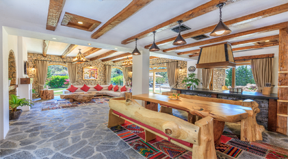 Open-plan stone living room with natural wood beams and rustic dining area