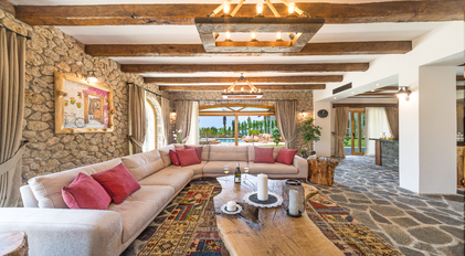 Rustic stone-and-wood living room with pool view at Villa Elmalı