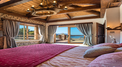Master bedroom with rustic wooden ceiling and sea-view terrace