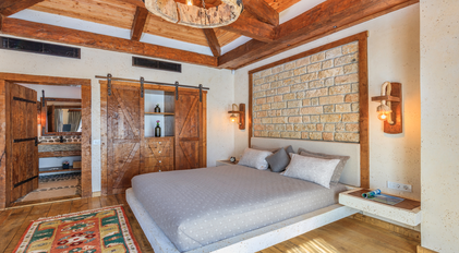 Master bedroom with stone feature wall and handcrafted wood detailing
