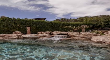 Natural rock pool with cascading waterfall surrounded by lush greenery