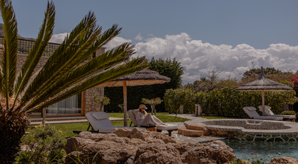 Guest relaxing by the pool under a thatched parasol