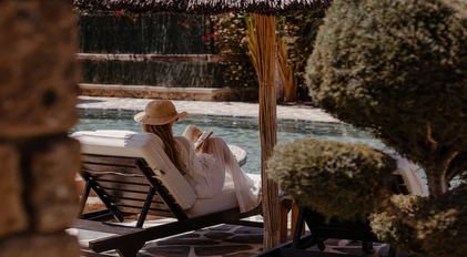 Guest relaxing on a sunbed by the natural stone pool