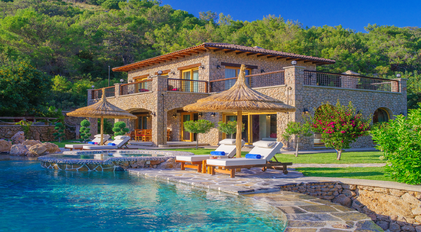 Stone villa facade with private pool and sun terrace in a forested setting