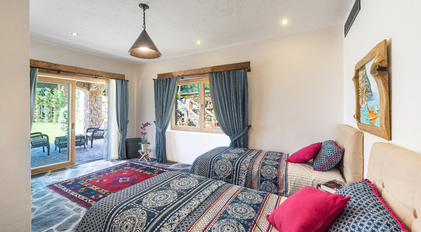 Twin bedroom with garden terrace access in a stone-built villa
