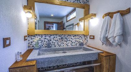 Stone-accent bathroom vanity with handcrafted wooden details and soft Mediterranean light