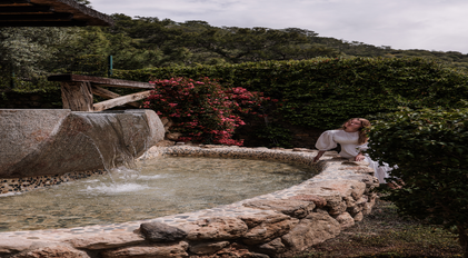 Stone garden water feature beside bougainvillea and rustic wooden details