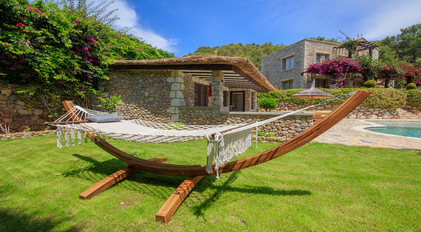 Garden hammock overlooking stone guesthouse and Mediterranean landscape