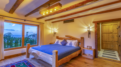Master bedroom with evening sea view and handcrafted wooden bed at Villa Gemile