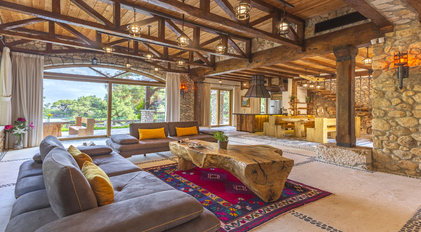 Open-plan stone living room with rustic beams and natural wooden furnishings