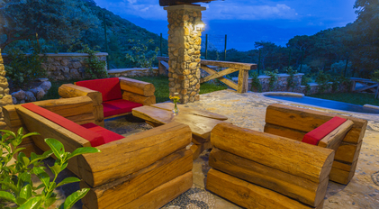 Outdoor stone terrace with handcrafted log seating and distant sea views