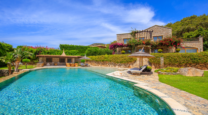 Expansive pool panorama with stone estate architecture and Mediterranean greenery