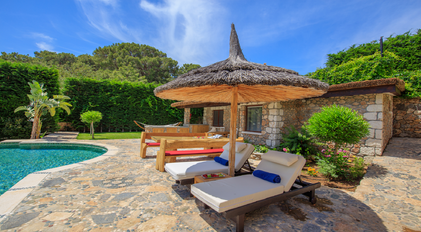 Shaded poolside loungers beside stone guesthouse terrace at Villa Gemile