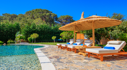 Poolside sunloungers beside a natural-style Mediterranean pool surrounded by forest