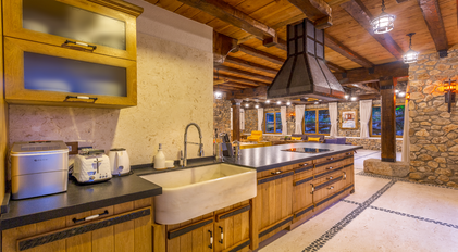 Rustic open-plan kitchen with stone walls and handcrafted wooden cabinetry