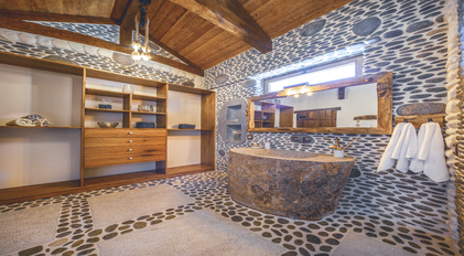 Panoramic stone-textured bathroom with handcrafted wooden elements and natural light