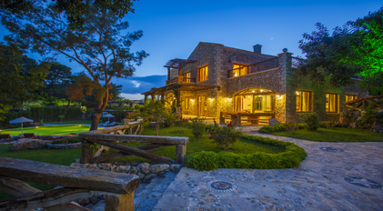 Stone villa architecture illuminated at dusk with landscaped Mediterranean gardens