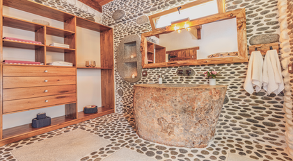 Handcrafted stone bathroom with natural carved sink and pebble walls