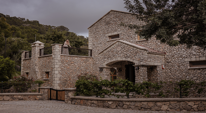 Stone villa entrance with upper terrace and Mediterranean surroundings