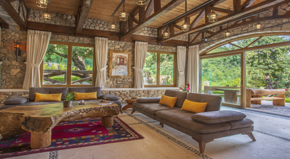 Stone living room with garden-view windows and handcrafted wooden furnishings