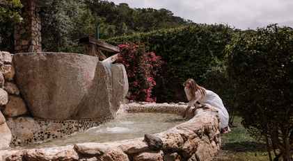 Stone waterfall feature surrounded by Mediterranean greenery and rustic textures