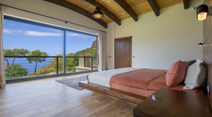 Bedroom with large panoramic window overlooking the Aegean hills