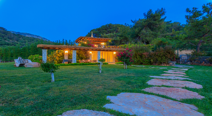 Night garden terrace surrounded by pine forest and softly illuminated stone pergola
