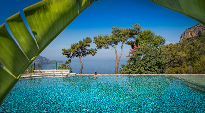 Infinity pool overlooking the Mediterranean and forested cliffs