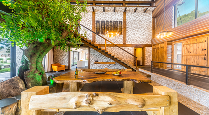 Spacious living area with indoor tree and handcrafted wooden staircase