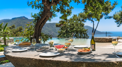 Shaded outdoor lunch table beside the infinity edge with bay panorama
