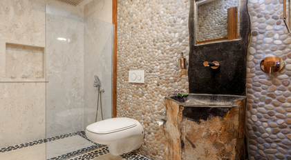 Pebble-stone bathroom with natural carved sink and walk-in shower