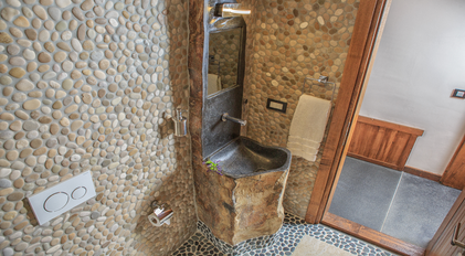 Rustic stone-accent powder room with sculpted natural rock washbasin