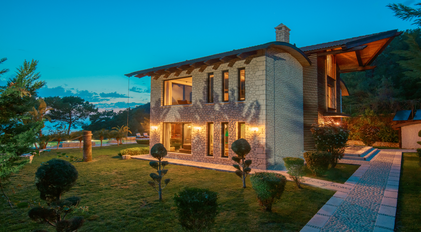 Stone-architecture villa with illuminated garden path overlooking a quiet peninsula